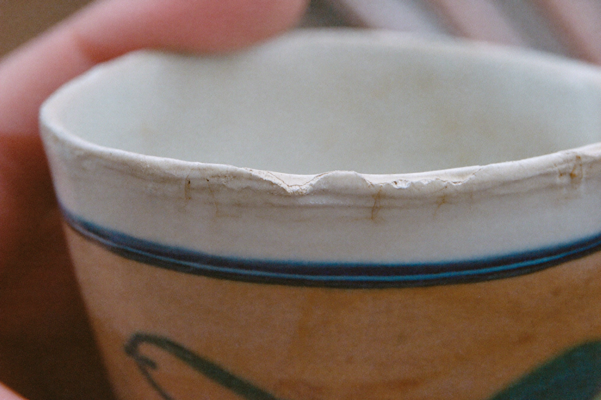 The chipped, finely crazed glazed rim of an old ceramic cup