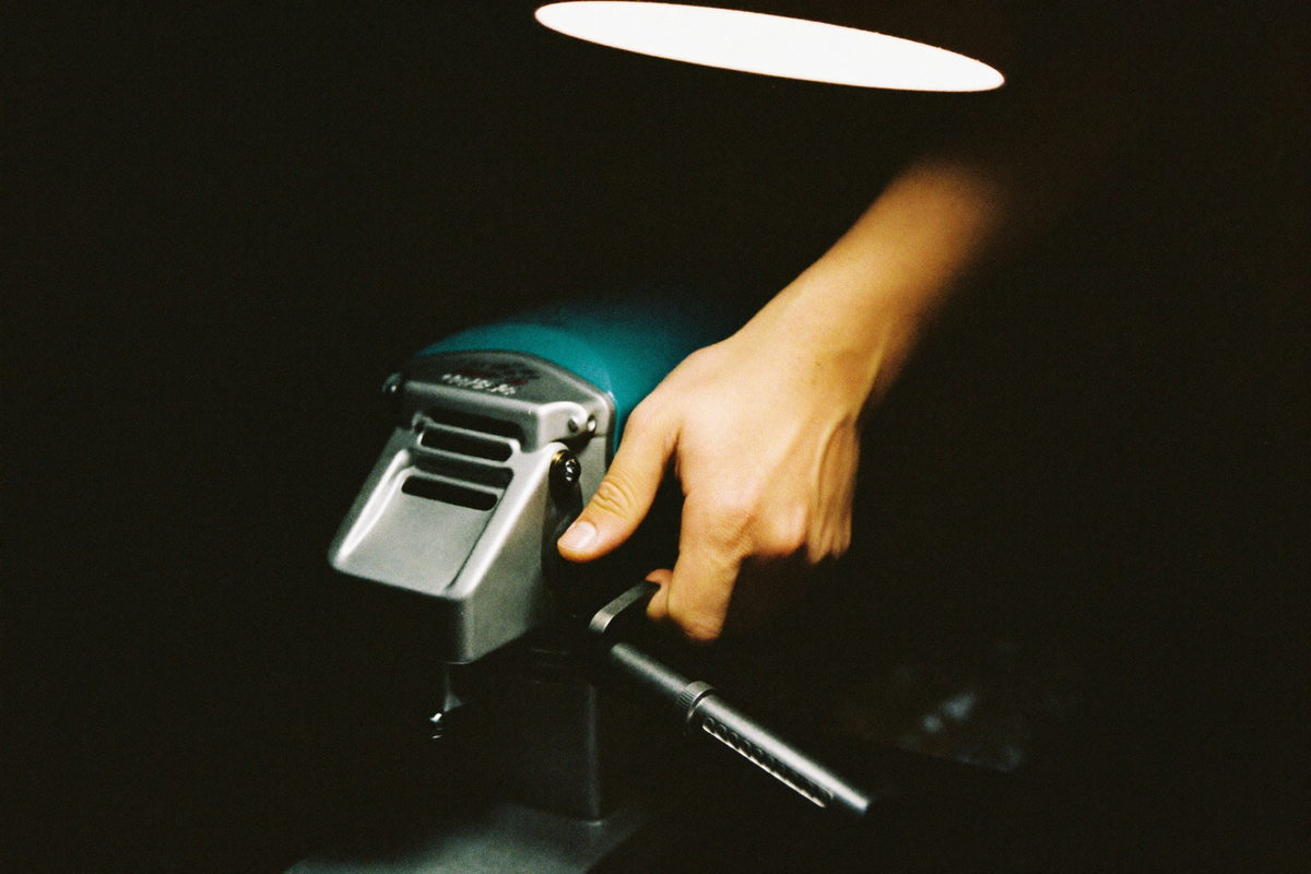 A hand turning a grinder adjustment collar by one notch