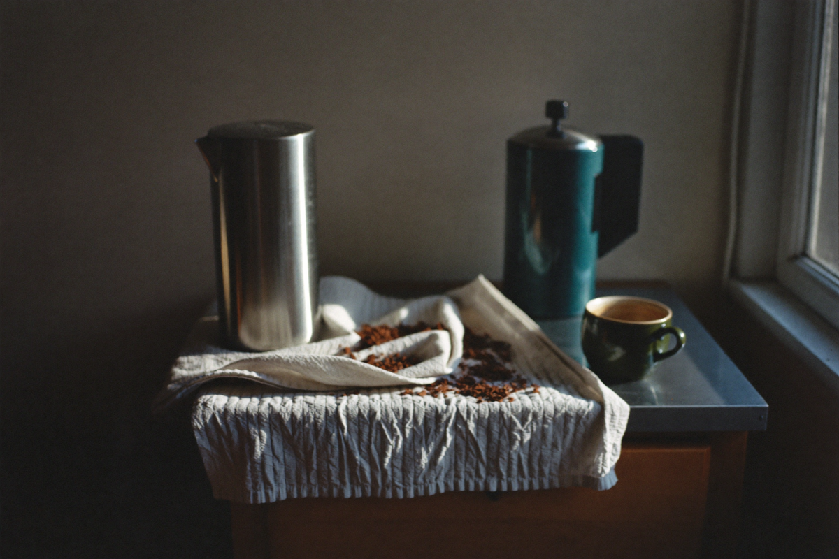 A portafilter and spent grounds on a cluttered kitchen counter at dawn