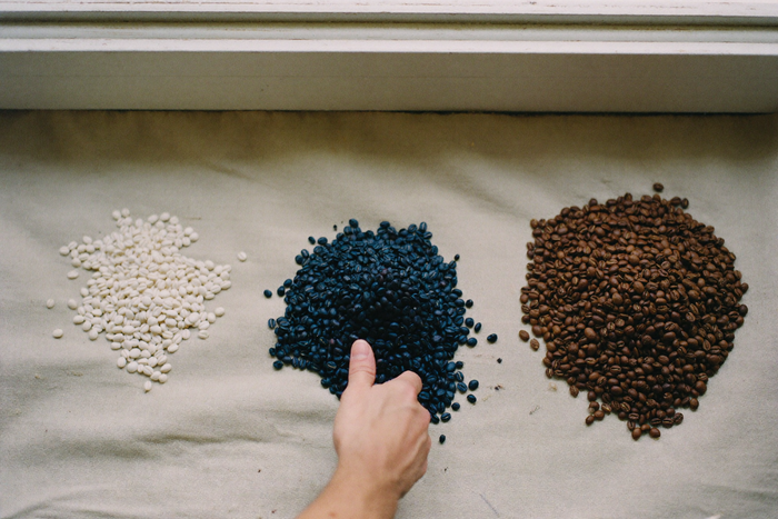Three heaps of differently processed coffee beans on linen