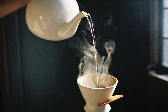 A thin ribbon of water falling into a dripper through a shaft of light