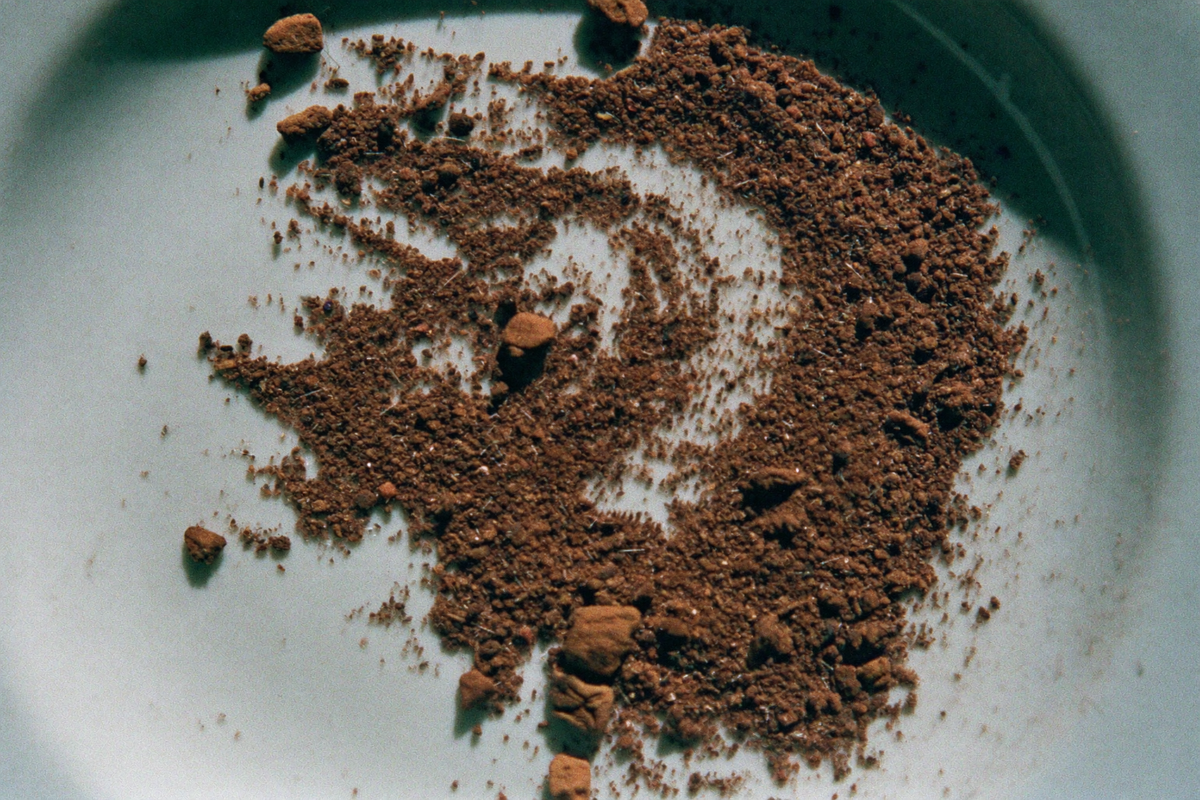 Unevenly ground coffee on a white saucer, dust beside large chips