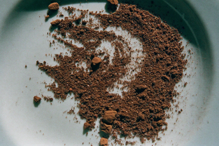 Unevenly ground coffee on a white saucer, dust beside large chips