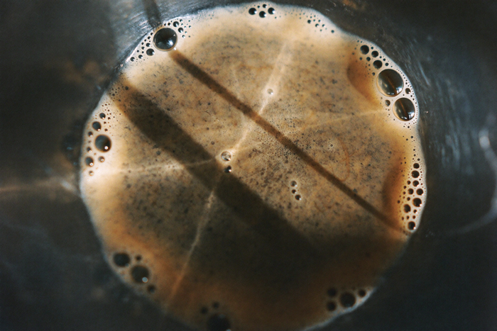 A bed of wet coffee grounds blooming, bubbles breaking on the surface