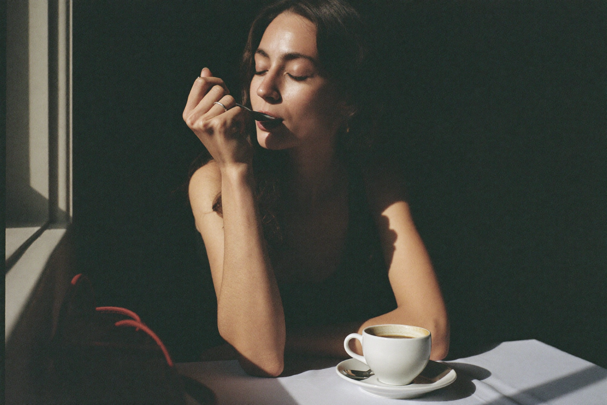 A woman tasting coffee from a spoon with her eyes closed